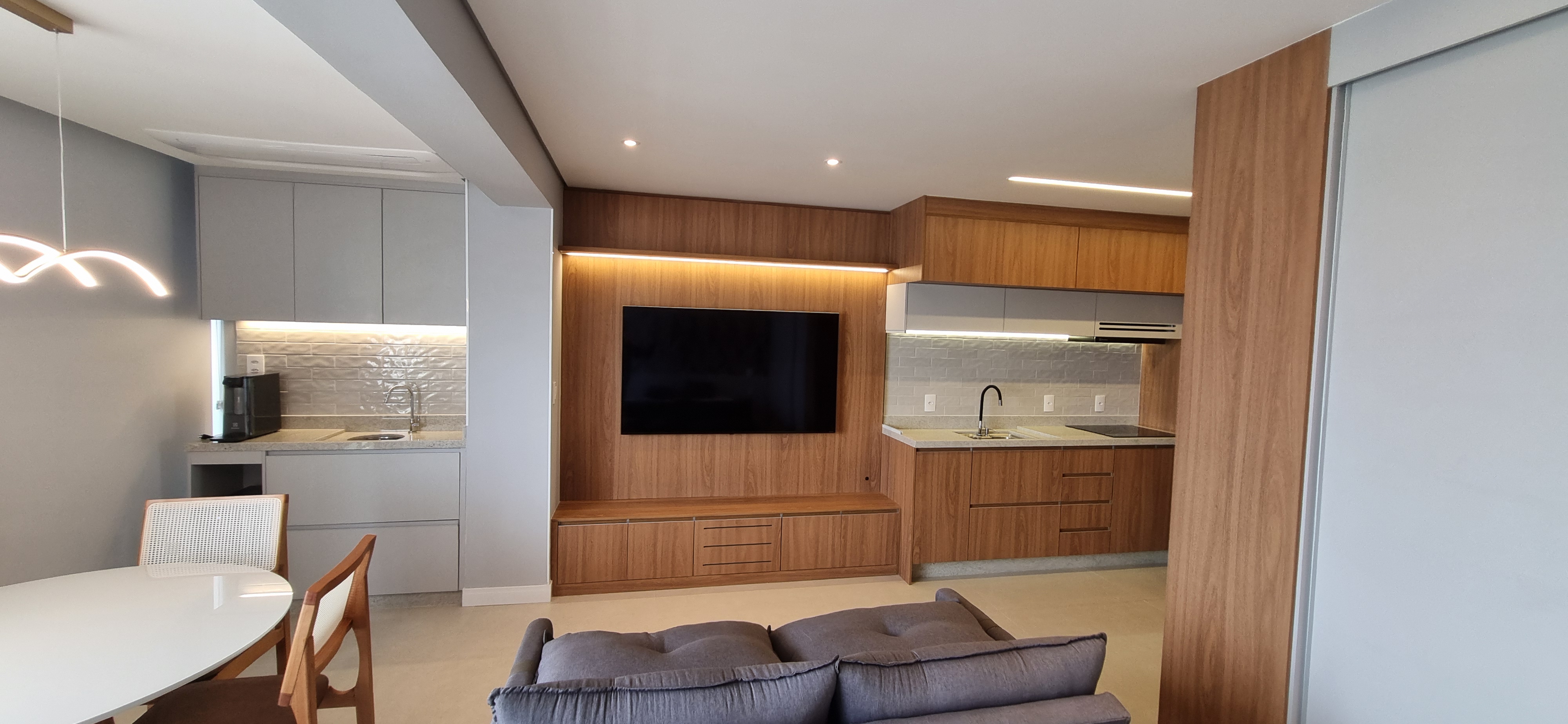 Sala integrada com painel, cozinha e móveis planejados